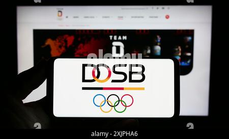 Stoccarda, Germania, 06-17-2023: Persona con smartphone con logo organizatin Deutscher Olympischer Sportbund (DOSB) sullo schermo di fronte Foto Stock