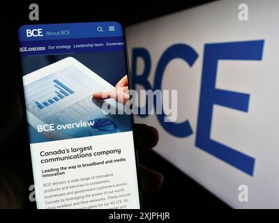 Stoccarda, Germania, 06-23-2023: Persona che possiede uno smartphone con pagina web della società canadese di telecomunicazioni BCE Inc. Su schermo con logo. Concentrati su Foto Stock
