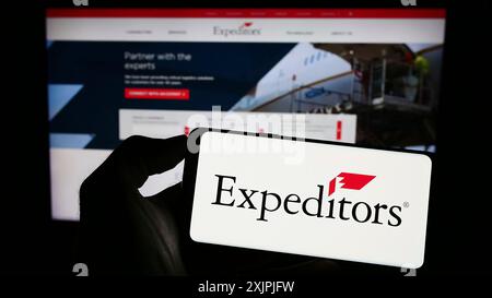 Stoccarda, Germania, 07-01-2023: Persona che tiene un cellulare con il logo di Expeditors International of Washington Inc. Sullo schermo davanti all'azienda Foto Stock