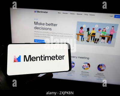 Stoccarda, Germania, 07-09-2023: Persona che detiene un cellulare con il logo della società di software di presentazione Mentimeter sullo schermo davanti all'azienda Foto Stock