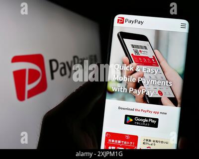 Stoccarda, Germania, 07-19-2023: Persona che detiene uno smartphone con pagina web della società di pagamento giapponese PayPay Corporation sullo schermo con logo. Concentrati su Foto Stock