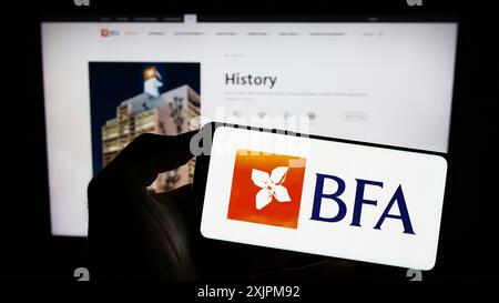 Stoccarda, Germania, 07-21-2023: Persona che detiene il cellulare con il logo della società finanziaria Banco de Fomento Angola (BFA) sullo schermo di fronte alla pagina web. Foto Stock