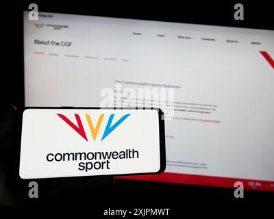 Stoccarda, Germania, 07-30-2023: Persona con smartphone con logo dell'organizzazione Commonwealth Games Federation (CGF) sullo schermo di fronte Foto Stock