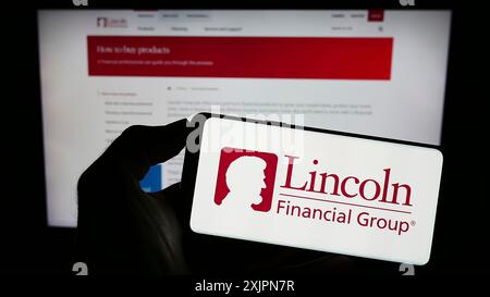 Stoccarda, Germania, 08-02-2023: Persona che tiene il cellulare con il logo della società finanziaria statunitense Lincoln National Corporation sullo schermo di fronte Foto Stock