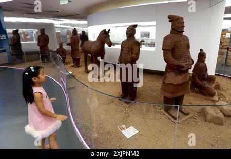 Pechino, la provincia cinese dello Shaanxi. 18 luglio 2024. Una ragazza ammira le repliche di cioccolato dei Guerrieri di Terra cotta in un museo del cioccolato nel Great Tang All Day Mall a Xi'an, nella provincia Shaanxi del nord-ovest della Cina, 18 luglio 2024. Il museo del cioccolato, che copre un'area di 10.000 metri quadrati, espone più di 100 creazioni di cioccolato a tema sull'antica architettura cinese e le reliquie culturali che attraggono molti visitatori. Crediti: Liang Aiping/Xinhua/Alamy Live News Foto Stock