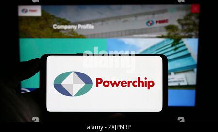 Stoccarda, Germania, 08-06-2023: Persona che detiene un cellulare con il logo della società Powerchip Technology Corporation (PSMC) sullo schermo davanti alla pagina web. Foto Stock