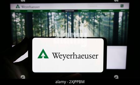 Stoccarda, Germania, 08-12-2023: Persona che possiede uno smartphone con il logo della società Weyerhaeuser statunitense timberland sullo schermo davanti al sito web. Foto Stock