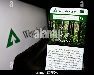 Stoccarda, Germania, 08-12-2023: Persona con smartphone con pagina web della società Weyerhaeuser statunitense timberland sullo schermo con logo. Concentrati su Foto Stock