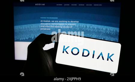 Stoccarda, Germania, 08-14-2023: Persona che tiene il cellulare con il logo della società americana di biotecnologie Kodiak Sciences Inc. Sullo schermo di fronte Foto Stock