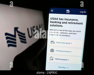 Stoccarda, Germania, 08-20-2023: Persona che tiene il cellulare con la pagina web della United Services Automobile Association (USAA) sullo schermo davanti al logo. Foto Stock