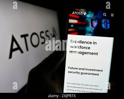 Stoccarda, Germania, 08-20-2023: Persona che detiene uno smartphone con pagina web della società di gestione della forza lavoro Atoss software AG sullo schermo con logo. Concentrati Foto Stock