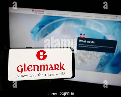 Stoccarda, Germania, 08-25-2023: Persona che detiene uno smartphone con il logo della società indiana Glenmark Pharmaceuticals Limited sullo schermo davanti al sito web. Foto Stock