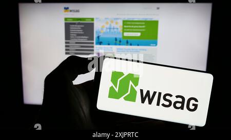 Stoccarda, Germania, 08-28-2023: Persona che detiene il cellulare con il logo della società tedesca WISAG Dienstleistungsholding se sullo schermo di fronte alla pagina web. Foto Stock