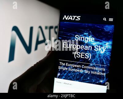 Stoccarda, Germania, 09-08-2023: Persona che possiede uno smartphone con pagina web dell'operatore britannico di controllo del traffico aereo NATS Limited sullo schermo con logo. Foto Stock