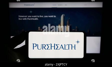 Stoccarda, Germania, 09-08-2023: Persona con smartphone con logo della società emiratina Pure Health LLC (PureHealth) sullo schermo di fronte al sito web. Foto Stock