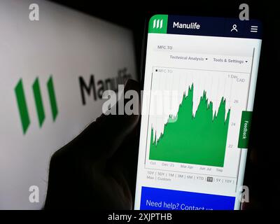 Stoccarda, Germania, 09-11-2023: Persona che detiene il cellulare con pagina web della società canadese Manulife Financial Corporation sullo schermo con logo. Concentrati Foto Stock