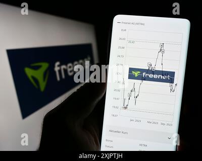 Stoccarda, Germania, 09-10-2023: Persona che detiene il cellulare con pagina web della società tedesca di telecomunicazioni Freenet AG su schermo con logo. Concentrati su Foto Stock