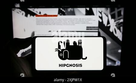 Stoccarda, Germania, 09-18-2023: Persona che detiene il cellulare con il logo della società di investimento Hipgnosis Songs Fund Limited sullo schermo di fronte alla pagina web. Foto Stock