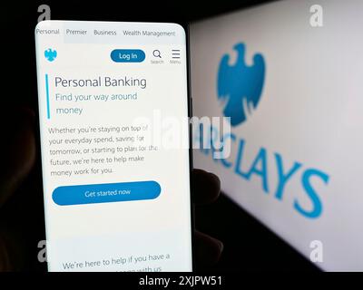 Stoccarda, Germania, 09-18-2023: Persona con smartphone con pagina web della banca universale britannica Barclays plc sullo schermo davanti al logo. Concentrati su Foto Stock