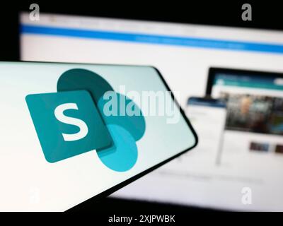 Stoccarda, Germania, 09-21-2023: Cellulare con logo della piattaforma collaborativa Microsoft SharePoint sullo schermo di fronte al sito Web aziendale. Concentrati su Foto Stock