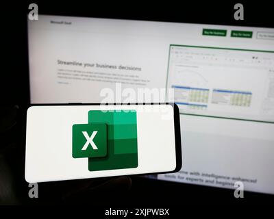 Stoccarda, Germania, 09-21-2023: Persona che tiene il cellulare con il logo dell'editor di fogli di calcolo Microsoft Excel sullo schermo davanti alla pagina Web aziendale. Foto Stock