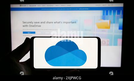 Stoccarda, Germania, 09-21-2023: Persona che possiede uno smartphone con logo del servizio di hosting di file Microsoft OneDrive sullo schermo davanti al sito Web. Concentrati Foto Stock