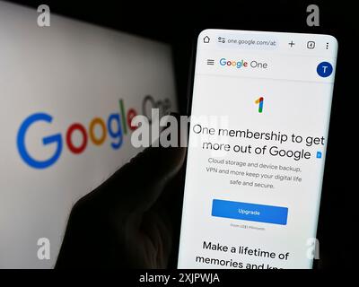 Stoccarda, Germania, 09-23-2023: Persona che possiede uno smartphone con pagina web del servizio di abbonamento software Google One sullo schermo davanti al logo. Concentrati Foto Stock