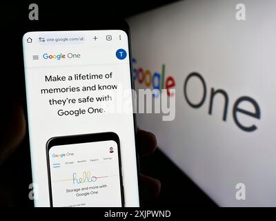 Stoccarda, Germania, 09-23-2023: Persona che detiene un cellulare con pagina web del servizio di abbonamento software Google One sullo schermo davanti al logo. Concentrati Foto Stock