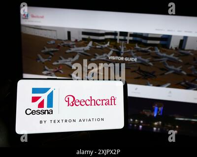 Stoccarda, Germania, 09-25-2023: Persona che detiene un telefono cellulare con il logo della società aeronautica americana Textron Aviation Inc. Davanti al business web Foto Stock