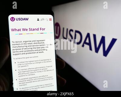 Stoccarda, Germania, 09-27-2023: Persona che detiene un telefono cellulare con pagina web dell'Union of Shop distributive and Allied Workers (USDAW) con logo. Concentrati Foto Stock