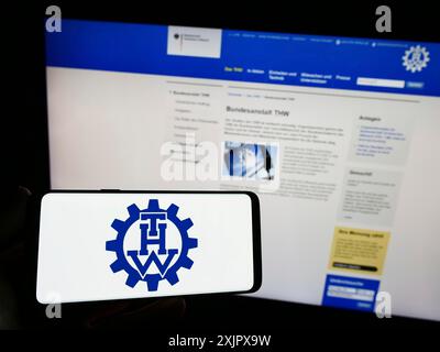 Stoccarda, Germania, 10-08-2023: Persona con smartphone con logo dell'organizzazione Bundesanstalt Technisches Hilfswerk (THW) davanti al sito web. Foto Stock