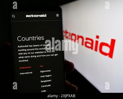 Stoccarda, Germania, 10-08-2023: Persona con smartphone e pagina web dell'organizzazione benefica internazionale ActionAid davanti al logo. Concentrati su Foto Stock