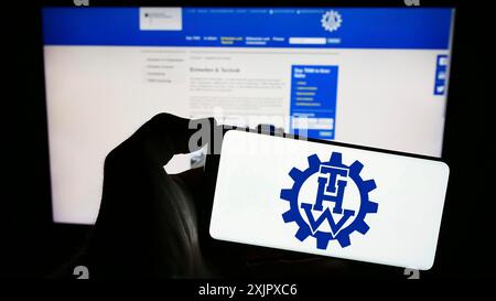 Stoccarda, Germania, 10-08-2023: Persona che detiene il cellulare con il logo dell'organizzazione Bundesanstalt Technisches Hilfswerk (THW) davanti alla pagina web. Foto Stock