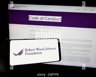 Stoccarda, Germania, 11-03-2023: Persona con smartphone con logo dell'organizzazione statunitense Robert Wood Johnson Foundation (RWJF) davanti al sito web. Foto Stock