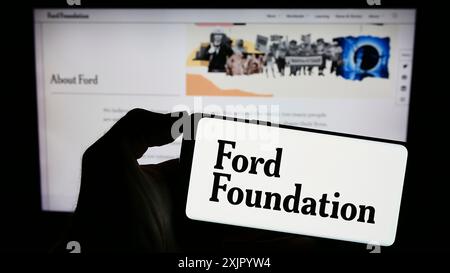 Stoccarda, Germania, 11-02-2023: Persona che tiene il cellulare con il logo dell'organizzazione caritatevole statunitense Ford Foundation davanti alla pagina web. Concentrati sul telefono Foto Stock