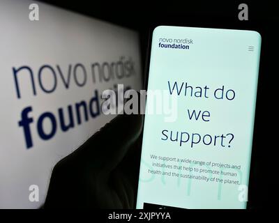Stoccarda, Germania, 11-02-2023: Persona che detiene il cellulare con pagina web dell'organizzazione danese Novo Nordisk Foundation davanti al logo. Concentrati su Foto Stock
