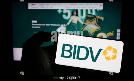 Stoccarda, Germania, 11-03-2023: Persona che detiene un telefono cellulare con il logo della Banca commerciale per gli investimenti e lo sviluppo del Vietnam davanti al web Foto Stock