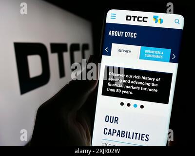 Stoccarda, Germania, 11-03-2023: Persona che detiene uno smartphone con sito web della società statunitense Depository Trust and Clearing Corporation (DTCC) con logo. Foto Stock