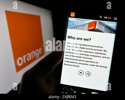 Stoccarda, Germania, 11-03-2023: Persona che detiene un cellulare con pagina web della società francese di telecomunicazioni Orange SA davanti al logo aziendale. Concentrati Foto Stock