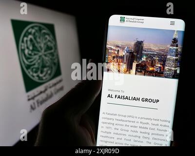 Stoccarda, Germania, 11-06-2023: Persona che detiene il cellulare con pagina web della società saudita al Faisaliah Group davanti al logo. Concentrati sul centro Foto Stock