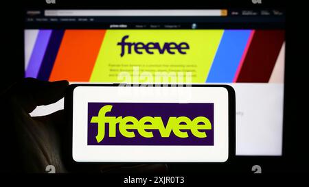 Stoccarda, Germania, 11-11-2023: Persona che tiene un telefono cellulare con il logo del servizio di streaming video-on-demand americano Amazon Freevee davanti al web Foto Stock