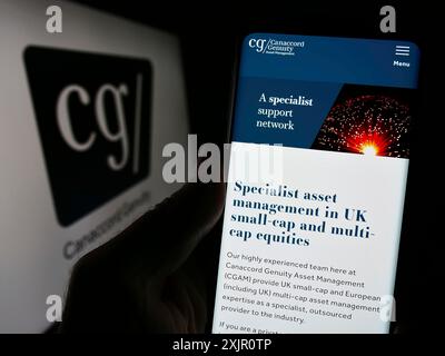 Stoccarda, Germania, 11-11-2023: Persona che detiene il cellulare con pagina web della società finanziaria canadese Canaccord Genuity Group Inc. Con logo. Concentrati su Foto Stock