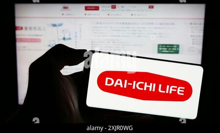 Stoccarda, Germania, 11-11-2023: Persona che detiene il cellulare con il logo dell'azienda giapponese dai-ichi Life Insurance Company Limited davanti alla pagina web. Foto Stock