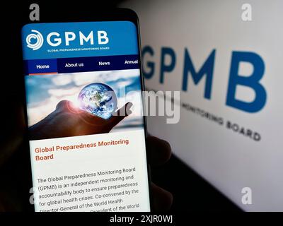 Stoccarda, Germania, 11-11-2023: Persona che tiene un cellulare con pagina web del Global Preparedness Monitoring Board (GPMB) davanti al logo. Concentrati su Foto Stock