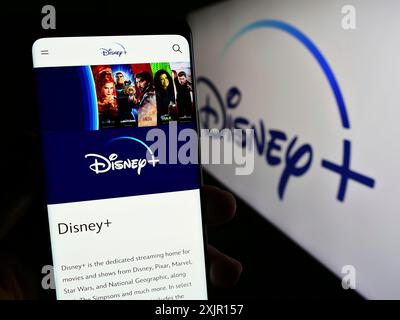 Stoccarda, Germania, 11-14-2023: Persona che tiene un cellulare con pagina web del servizio di streaming video on demand statunitense Disney Plus davanti al logo. Concentrati su Foto Stock