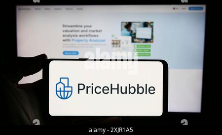 Stoccarda, Germania, 11-15-2023: Persona che detiene lo smartphone con il logo della società svizzera di analisi immobiliare PriceHubble AG davanti al sito web. Concentrati Foto Stock