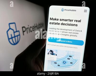 Stoccarda, Germania, 11-15-2023: Persona che detiene il cellulare con pagina web della società svizzera di analisi immobiliari PriceHubble AG davanti al logo. Concentrati Foto Stock