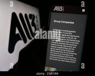Stoccarda, Germania, 11-27-2023: Persona che detiene il cellulare con pagina web della società di produzione televisiva britannica All3Media Limited con logo. Concentrati su Foto Stock