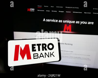 Stoccarda, Germania, 11-24-2023: Persona con smartphone con logo della società britannica di servizi finanziari Metro Bank plc davanti al sito web. Concentrati Foto Stock