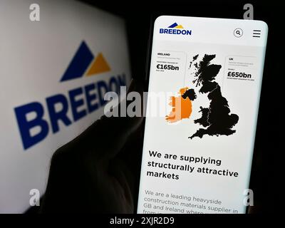 Stoccarda, Germania, 12-05-2023: Persona che detiene lo smartphone con pagina web della società britannica di materiali edili Breedon Group plc con logo. Concentrati Foto Stock